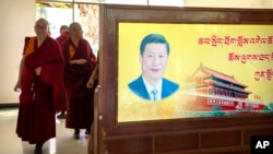 西藏拉萨一所寺庙的喇嘛走过习近平的画像屏风。(2021年5月31日)