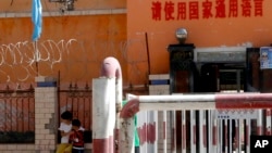 新疆喀什地区伽师县一所小学校门有铁丝网和监控镜头,校门前写着:请使用国家通用语言。(2018年8月31日)