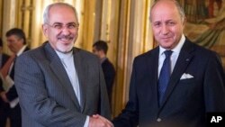 FILE - French foreign minister Laurent Fabius, right, poses for photographers with his Iranian counterpart Jawad Zarif prior to their meeting at the Quai d'Orsay in Paris, France, Nov. 5, 2013.
