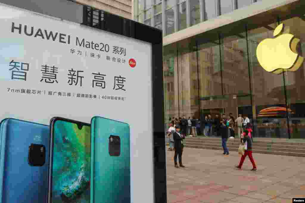 2018年10月26日在中国上海的Apple商店外面,顾客排队购买新的iPhone XR手机,附近有华为Mate 20系列产品的广告。华为使用竞争对手苹果的手机发推后,有网民说:“连华为员工都觉得iPhone比较好用” 。