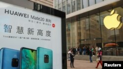 中国上海的苹果商店外面,顾客排队购买新的iPhone XR手机,附近有华为Mate 20系列产品的广告。(2018年10月26日)