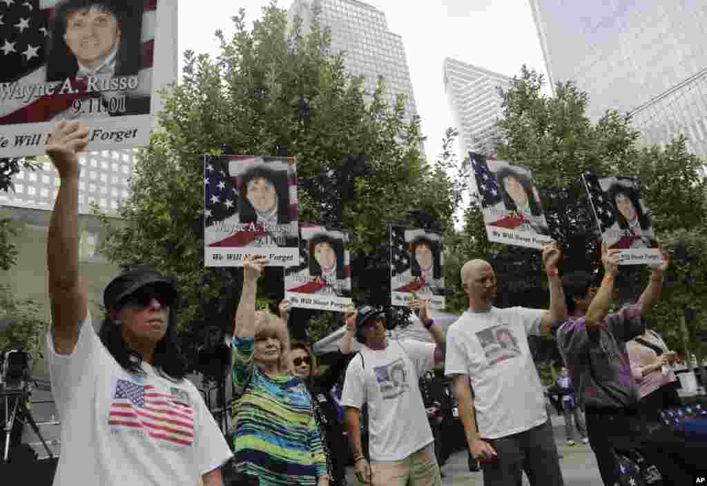 Friends and family of Wayne Russo hold up photographs of him as his name is read aloud during memorial observances held at the site of the World Trade Center in New York, Sept. 11, 2014.