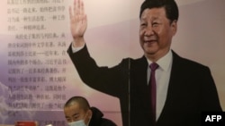 中国辽宁省沈阳市的一家书店里一名戴着口罩的读者坐在中国国家领导人习近平的大幅画像前。(2020年4月23日)