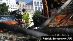 美国华盛顿,一名工人在抗议乔治·弗洛伊德(George Floyd)死亡的抗议活动后清理人行道上燃烧的杂物。