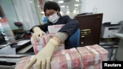 中国江苏省南通市一家银行的职员戴着口罩整理人民币钞票。(2020年1月30日)