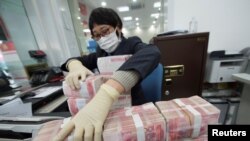 中国江苏省南通市一家银行的职员戴着口罩整理人民币钞票(2020年1月30日)