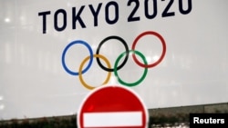 东京街头交通警示牌后的东京奥运会的标识。(2020年3月23日)