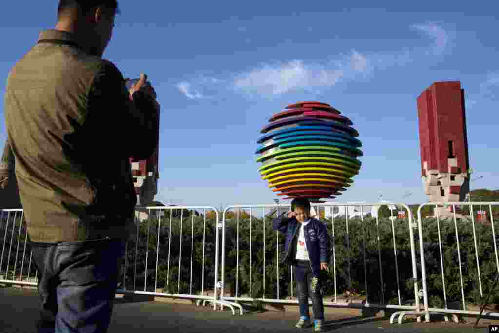 2014年11月6日,一名男孩在APEC北京峰会标志附近拍照。为了能让与会者呼吸到清新空气,中国政府采取了一系列强制措施,用洪荒之力创造了APEC蓝,在过去还创造过北京奥运蓝,但是终非长久之计。