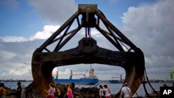 FILE - Tourists walk past an excavator shovel at the harbor of Havana, Cuba,Aug. 20, 2013.