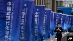 资料照:一名男子走过上海街头插满的宣传旗帜:“中国式现代化与世界”。 (2023年4月21日)