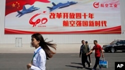 在广东珠海的第十二届中国国际航空航天展览会上,参观者走过中国喷气式战斗机的海报(2018年11月6日)。