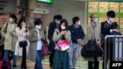 COVID-19 ပျံ့နှံ့မှု ကာကွယ်နိုင်ရေး တိုကျိုမြို့ ဘူတာရုံတခုတွင် ရထားစီးရန် စောင့်ဆိုင်းနေသည့် နှာခေါင်းစည်းတပ် ခရီးသည်များ။ (ဧပြီ ၆၊ ၂၀၂၀)