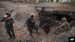 克伦民族解放军和人民防卫军成员在占领克伦邦妙瓦底镇南部一个政府军前哨后对两名被俘士兵进行检查。(2024年3月11日)