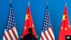 资料照 - 一次会议前,一位服务人员在仔细摆放美中两国国旗。