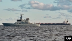 中国船舶“伊鹏3号”散货船(右)停泊在丹麦日德兰半岛附近的卡特加特海。丹麦海军巡逻艇(左前)正在进行监视。(2024年11月20日)