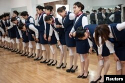 河北石家庄的空乘培训学校,想当空姐的学员们训练站立姿势和仪态,嘴里含着筷子以保持微笑,膝盖夹着纸张以保持并拢(2017年5月4日)