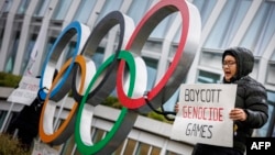 资料照片:西藏活动人士在位于瑞士洛桑的国际奥委会总部大门外手举抵制北京冬奥会的标语。(2021年12月11日)