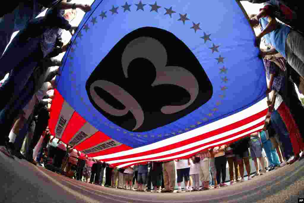 Visitors to the Flight 93 National Memorial hold a giant flag as they participate in a sunset memorial service at sunset in Shanksville, Pennsylvnia, Sept. 10, 2014.