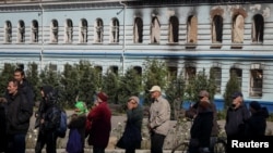 在新近被收复的乌克兰城镇伊久姆,当地居民排队领取人道救援物资。(2022年9月26日)