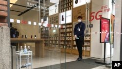 中国中部湖北省武汉市,一名商店员工在一条重新开放的零售街上等待顾客。(2020年3月30日)