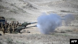 美军和菲律宾军队在联合演习中,发射M198榴弹炮击沉假想敌船。(法新社)