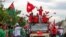 Supporters of the National League for Democracy (NLD) party on a motorcade pass supporters of the opposition Union Solidarity and Development Party (USDP), seen at left, during a campaign in Wundwin, near Mandalay on September 19, 2020. (Photo by Kyaw The