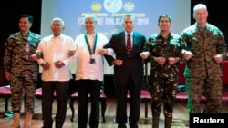 在马尼拉,美国和菲律宾官员在年度军演开幕式上手挽手(2016年4月4日)
