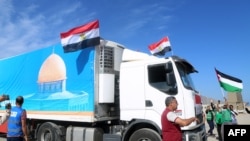 Người dân ở phía bên Ai Cập của cửa khẩu biên giới Rafah vui mừng khi đoàn xe tải chở hàng viện trợ nhân đạo đến Dải Gaza vào ngày 21 tháng 10 năm 2023.