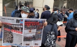 手持香港《苹果日报》的香港市民梁先生在西九法院大楼外排队,他形容防疫限聚令使香港成为一个大监狱,3月1日逾千人排队声援47名被控国安法的民主派人士有如”放监” (美国之音/汤惠芸)