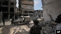 2024年9月13日,以色列士兵在加沙地带被以色列军队摧毁的建筑物旁。