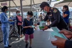 戴着防护口罩的泰国卫生官员在曼谷的一个商场里发放口罩。(2020年1月28日)