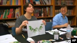 Undergraduate student Moe Lewis, left, shows her watercolor painting of peony leaves at a traditional Chinese painting class at the Confucius Institute at George Mason University in Fairfax, Va., on May 2, 2018.