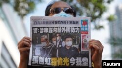 在香港法院审理壹传媒和苹果日报高管期间,一名支持者手举香港苹果日报站在法院外。(2021年6月19日)