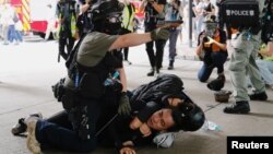 香港警察在逮捕一名参加反对港版国安法游行示威者的同时举起手中的胡椒喷剂手枪。(2020年7月1日)