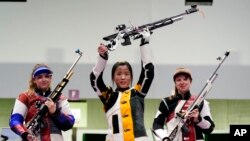 中国选手杨倩在女子10米气步枪的比赛中摘取本届奥运会首枚金牌后将步枪举起(2021年7月24日)