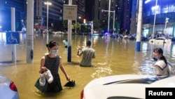 中国安徽合肥的民众在被洪水淹没的街道上过马路。(2020年6月27日)