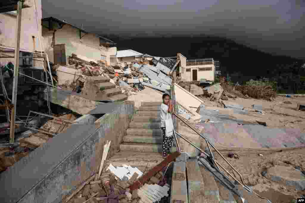 2018年9月18日,台风之后,香港石澳沿海村庄的海滩附近的学校,一名妇女站在倒塌的建筑物前。