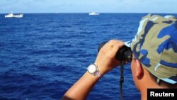 资料照:一名越南海警船成员在有争议的南中国海上观察中国海警船。(2014年7月15日)