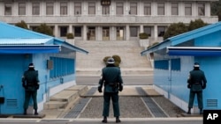 在朝韩边界板门店,三名站立的韩国士兵在注视北面灰色建筑的朝鲜一方(2014年3月12日 资料照片)