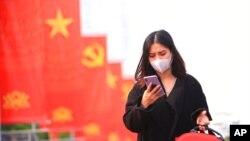 资料照片:越南河内一名女性带着口罩查看手机(2021年1月23日)