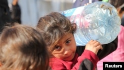 一名加沙地区巴勒斯坦儿童拿着一个水容器,正在等待取水。人权组织报告指控以色列在加沙剥夺水源是一种种族灭绝行为。(路透社:2024年12月19日)