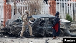 资料照片:阿富汗安全部队成员检查喀布尔一处爆炸现场被炸毁的汽车。(2020年12月20日)