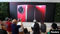 人们在北京的华为旗舰店现场观看华为新款三向折叠智慧型手机 Mate XT 的发表会。(路透社:2024年9月10日)