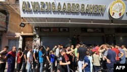 2023 年 10 月 15 日，在以色列对加沙地带南部汗尤尼斯的袭击中，流离失所的巴勒斯坦人排队领取面包。