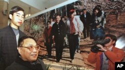 资料照:中国已故领导人邓小平的儿子邓朴方在北京军事博物馆举办的展览中观看了他父亲的一张大照片,由他的妹妹邓琳拍摄。(1998年2月18日)