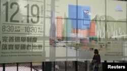 一名妇女走过香港举行立法会换届选举的广告 (2021年12月1日)