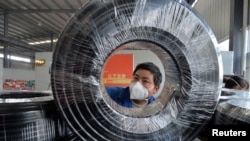 贵州省贵阳市一名戴着口罩的工人在缆线生产线上工作。(2020年2月25日)