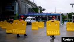 武汉火车站前工人搬走为防疫设置的路障。(2020年3月28日)