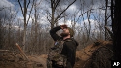 资料照片:在乌克兰顿涅茨克州巴赫穆特附近的阵地上,一名乌克兰军人仰望天空,确保没有无人机。(2024年3月25日)