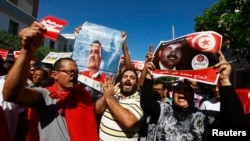 9月26日,突尼斯抗议民众在突尼斯城西南270公里的一个城市举行抗议,举着被暗杀的反对派领导人的肖像